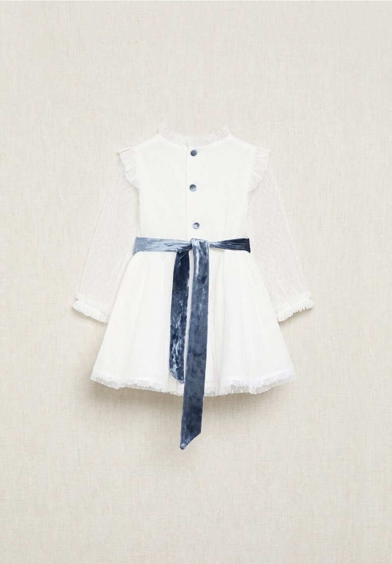 Robe blanche avec de longues manches transparentes, col volanté, fermeture à boutons sur le devant et une ceinture en velours bleu. Présente une dentelle au niveau de l'ourlet.