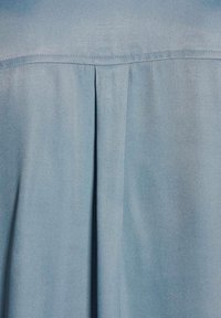 Lichtblauwe blouse van een zachte stof, met plooidetail aan de achterkant en een effen ontwerp met een subtiele glans.