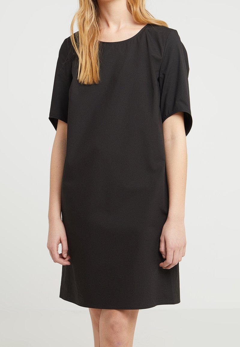 Schwarzes Kurzarmkleid aus glattem Stoff. Mit Rundhalsausschnitt und lockerer Passform, die bis zur Mitte des Oberschenkels reicht. Einfaches, minimalistisches Design.