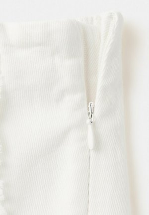 Detailný záber bielej časti látky s viditeľným bielym zipsom a textúrovaným diagonálnym vzorom tkania.