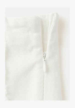 Gros plan sur une section de tissu blanc avec une fermeture éclair blanche visible et un motif de tissage diagonal texturé.