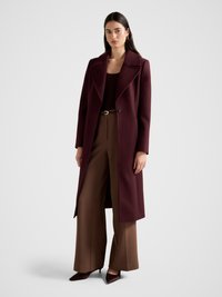 Burgundy wool coat with a notch lapel, single button closure, and long sleeves, worn over a brown top and high-waisted, wide-leg brown trousers.