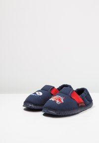 Marineblauwe slippers met rode accenten, voorzien van geborduurde ontwerpen van een brandweerwagen en een maan. Zacht materiaal, flexibele zool en instapstijl.