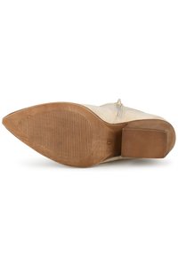 Botín de ante beige hasta el tobillo con punta redonda, cremallera lateral y suela de goma texturizada con un pequeño tacón cuadrado.