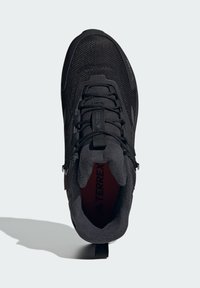 Čierna atletická obuv s textúrovaným sieťovinovým zvrškom, zaoblenou špičkou a polstrovaným golierom. Obsahuje čierne šnúrky a značkovú vnútornú podšívku.