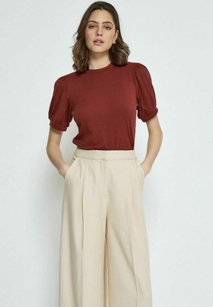 Brown ribbed short-sleeve top with puff shoulders, paired with high-waisted light beige trousers featuring side pockets.