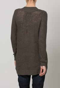 Langer, gestrickter Pullover in Dunkelgrau mit strukturiertem Muster, hohem Kragen und gerippten Bündchen. Der Saum reicht über die Hüften.