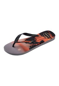 Tongs à bride noire unique avec un design de palmier et coucher de soleil orange et noir sur la semelle, marqué "Havaianas".
