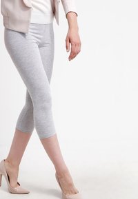Grijze capri-legging gemaakt van zacht, rekbaar materiaal. Gecombineerd met lichte nude hoge hakken, die een soepele, strakke vorm tonen.