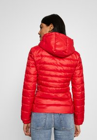 Rød dunjakke med hette, quiltet tekstur og elastiske mansjetter. Designet er tettsittende med en glatt overflate og lett materiale.