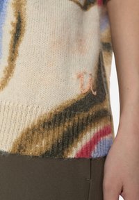 Beiger Strickpullover mit bunten abstrakten Mustern, verfügt über eine strukturierte Oberfläche und ein kleines gesticktes Logo am Saum.