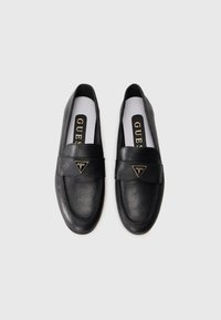 Black loafers made of textured leather, featuring a wide band and a triangular logo accent. Interior has a white insole with brand name.