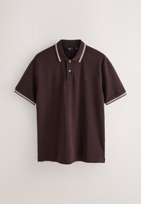 Polo à manches courtes marron foncé avec des rayures blanches et beiges sur le col et les bordures des manches, suspendu sur un fond uni.