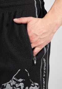 Zwarte gestructureerde shorts met een ritszak, grijze accenten en een grafische print. Elastische tailleband voor een comfortabele pasvorm.