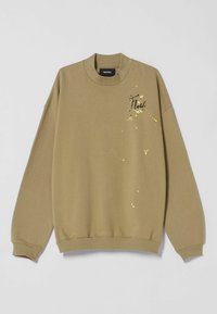 Kaki sweatshirt med rund hals, sänkta axlar och en svart "Flow."-tryck med gula stänkdetaljer på framsidan. Mjuk textur.