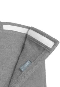 Graues Handtuch mit strukturiertem Stoff, an der Ecke gefaltet, mit einem weißen Klettband und einem kleinen blauen Etikett nahe dem Rand.