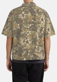 Short-sleeved, collared shirt in olive green with a floral and camo pattern. Lightweight fabric with a relaxed fit and straight hem.