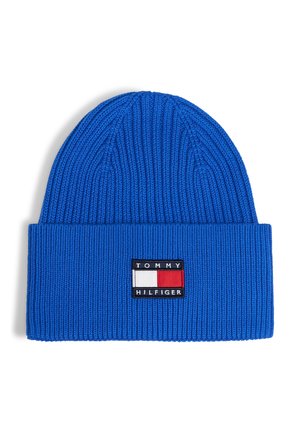 Bonnet en maille côtelée bleu avec revers, portant un patch rectangulaire du logo Tommy Hilfiger en rouge, blanc et noir à l'avant.