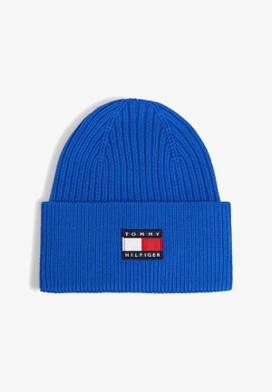 Niebieska prążkowana czapka z dzianiny z podwiniętym mankietem, z prostokątną naszywką z logo Tommy Hilfiger w kolorach czerwonym, białym i czarnym z przodu.