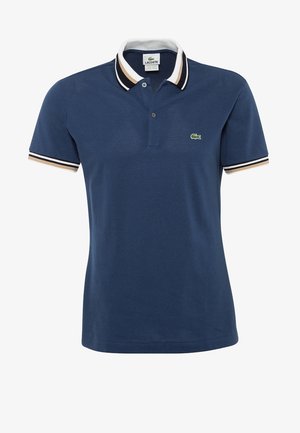 Marineblaues Lacoste Poloshirt mit weißem, beigem und schwarz gestreiftem Kragen und Ärmelbündchen, mit einem kleinen grünen Krokodil-Logo auf der Brust.
