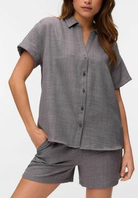 Camisa de botones de manga corta gris con cuello, que presenta una tela texturada y pantalones cortos gris a juego, ambos con un ajuste relajado.