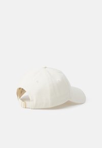 Hvit bomulls baseballcap med en buet skjerm, justerbar stropp bak, og ventilasjonshull på sidene.