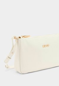 Sac en cuir blanc à bandoulière avec une finition texturée, fermeture éclair dorée et détail du logo. Dispose d'une bandoulière détachable pour plus de polyvalence.