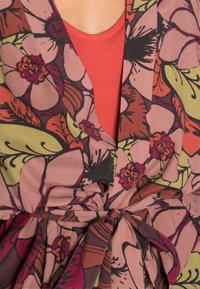 Bloemmotief wikkeltop met tinten roze, groen en bruin. Zachte stof met een geraffineerde taille en een v-hals ontwerp.