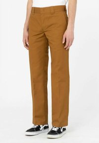 Braune gerade geschnittene Hose aus strapazierfähigem Stoff, mit klassischem Bund und seitlichen Taschen. Kombiniert mit schwarzen Sneakern.