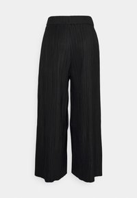 Pantalon noir à jambes larges avec plis verticaux, taille élastique et coupe ample, vu de dos sur fond uni.