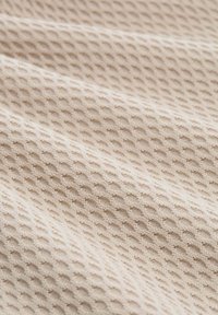 Gestructureerde stof in lichtbeige met een verhoogd, honingraatpatroon, dat een zachte, gebreide uitstraling laat zien. Subtiele variaties in diepte.