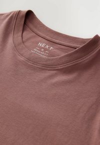 Brun bomulds T-shirt med rund hals, der har en regulær pasform label indeni. Blød tekstur og minimale designdetaljer.