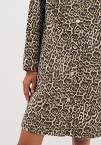 Leopardmönstrad klänning med långa ärmar, knappstängning, i beige, bruna och svarta nyanser; texturerad tyg; synlig sömnad och manschettdetalj.