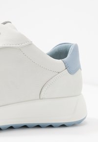 Sneaker bianca in pelle con morbidi accenti blu sul tallone e sul collo, caratterizzata da una superficie testurizzata, una forma slanciata e una suola in gomma a contrasto.