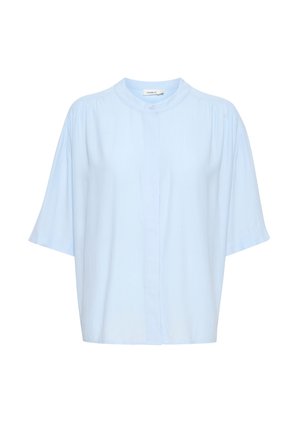 Camisa de manga corta de color azul claro con cuello mao, que presenta un cierre de botones y una textura sutil. Corte relajado con mangas ligeramente recogidas.
