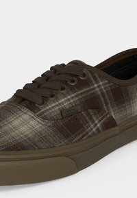 Кафяво и бежово карирано спортно обувка Vans с кафяви връзки и гумена подметка, отблизо показани странични и предни детайли.