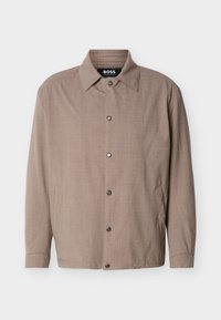 Μπεζ ανδρικό μπουφάν με γιακά, μακριά μανίκια, κουμπιά με πάτημα στο μπροστινό μέρος και πλαϊνές τσέπες, με την ετικέτα "BOSS" στο εσωτερικό του γιακά.