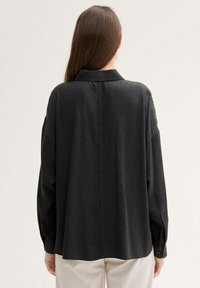 Dark gray long-sleeve shirt with a relaxed fit, collar, and button cuffs; features a smooth texture and back yoke design.