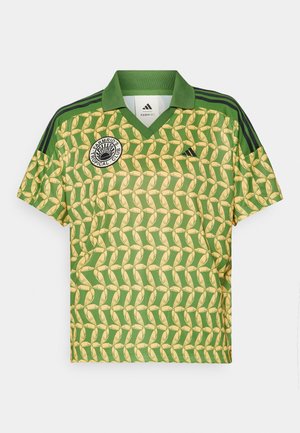 Groene en gele polo met korte mouwen en een bananenpatroon, V-hals en zwarte gestreepte schouders. Bevat een cirkelvormig logo op de linkerborst.