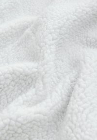 Witte fleece stof met een zachte, gestructureerde oppervlakte, met een lichte, gekreukelde uitstraling en een ongelijkmatige pool.