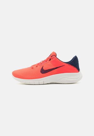 Zapatilla de running Nike de color coral brillante con logo Swoosh en azul marino, talón azul marino, suela blanca acolchada y diseño con cordones.