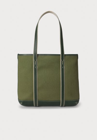 Olivengrønn canvas-handlenett med grønne skinn detaljer, to lange håndtak, kontrasterende søm og en rektangulær form.