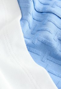 Tkanina z mieszanki bawełny, z teksturowaną niebieską częścią z wzorem tkanym w strukturę, połączona z gładką białą krawędzią.