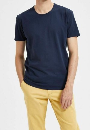 T-shirt en coton bleu marine avec un col rond et des manches courtes, associé à un pantalon jaune. Texture lisse avec une coupe classique.