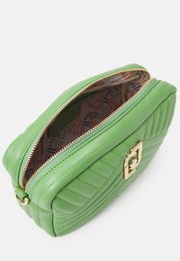 Groene, doorgestikte leren tas met gouden hardware, ritssluiting en een kleurrijke, gemusterde interieurvoering. Heeft een boxy vorm en een soepele textuur.