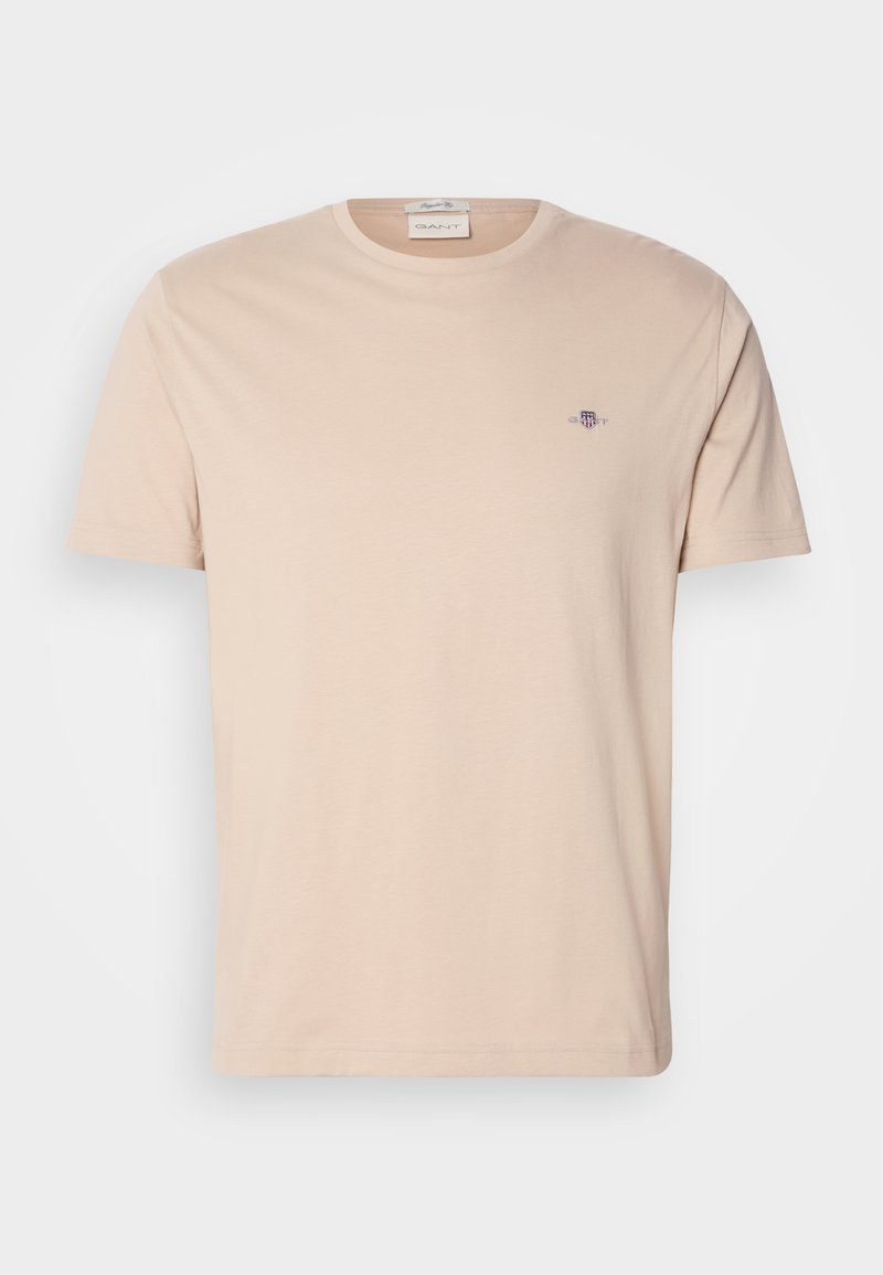 Helle beige Baumwoll-T-Shirt mit einem Rundhalsausschnitt. Verfügt über ein kleines gesticktes Logo auf der linken Brust. Gerader Saum und kurze Ärmel.