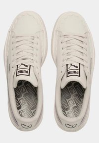 Bílé tenisky s hladkým koženým svrškem, vlnitým okrajem, plochými šňůrkami, gumovou podrážkou a vzorovanou stélkou s logem Puma.
