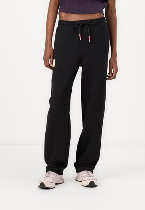 Pantaloni sportivi neri realizzati in morbido tessuto, con vita regolabile con cordino, tasche laterali e una piccola etichetta con logo sul davanti.