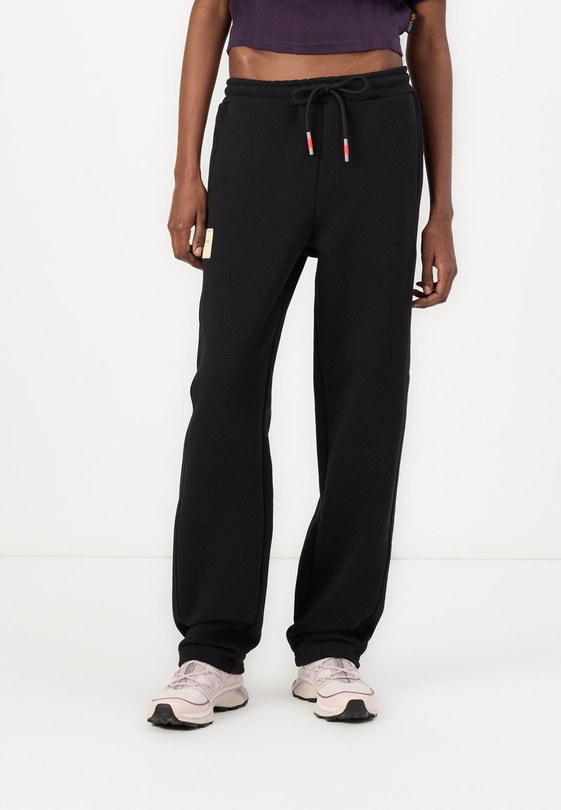 Sorte joggebukser laget av mykt stoff, med snor i livet, sidelommer og et lite logo-merke foran.