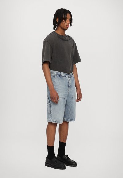 Gray oversized t-shirt, light blue denim shorts, black shoes, and socks. Features relaxed fit, button closure on shorts, and visible stitching.